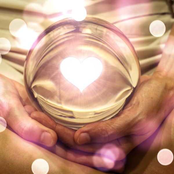 Spiritual background: Fortune teller concept, meditation hand with shining heart shape in magic glass ball,sign of love and peaceful